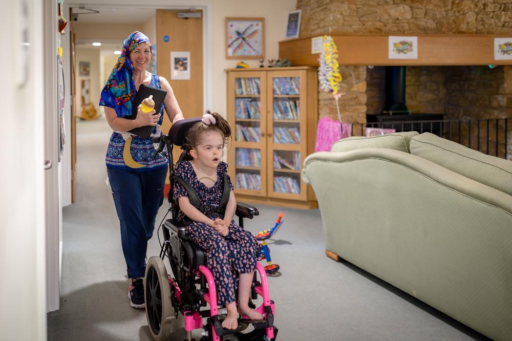 Girl using powerchair in hospice with carer